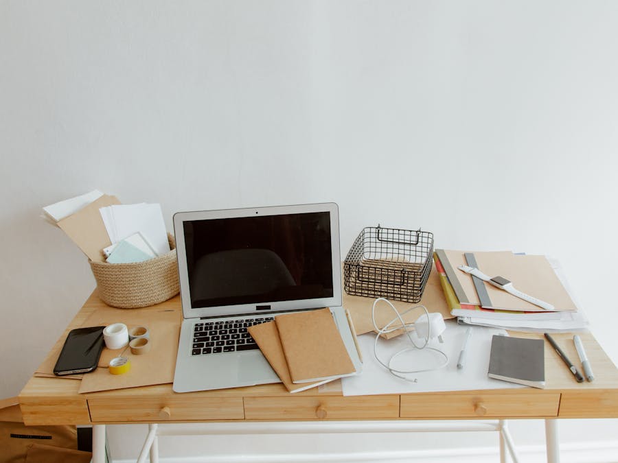 Clean and organized desk with a laptop, notebooks, and office supplies for productivity.