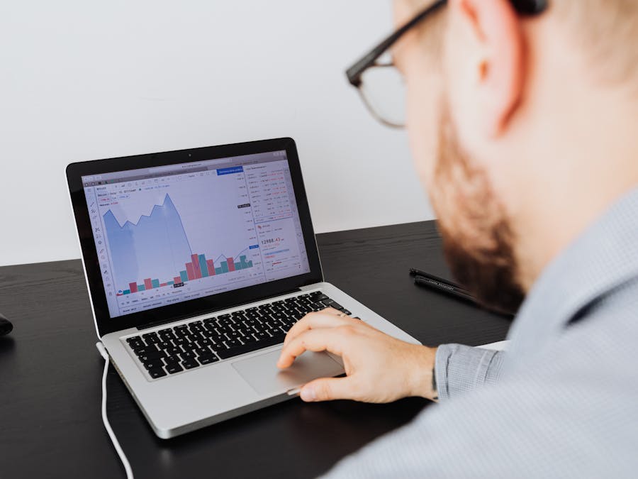 Man working on a laptop analyzing business data and financial graphs indoors.
