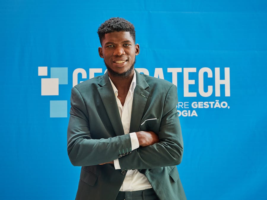 Businessman in suit smiling confidently with arms crossed at a technology event.