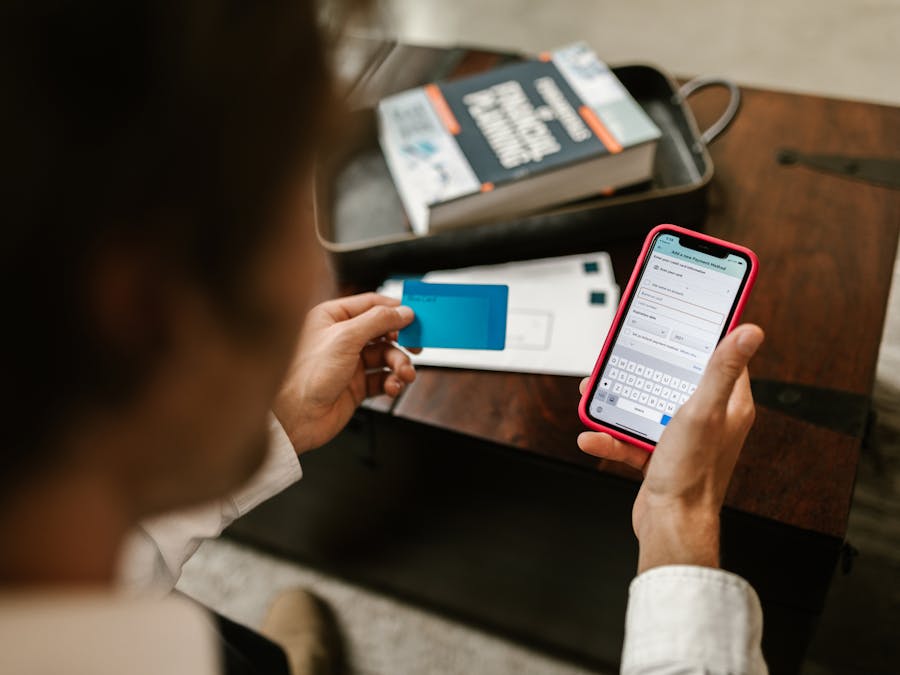 Person making an online payment using a smartphone and credit card indoors.