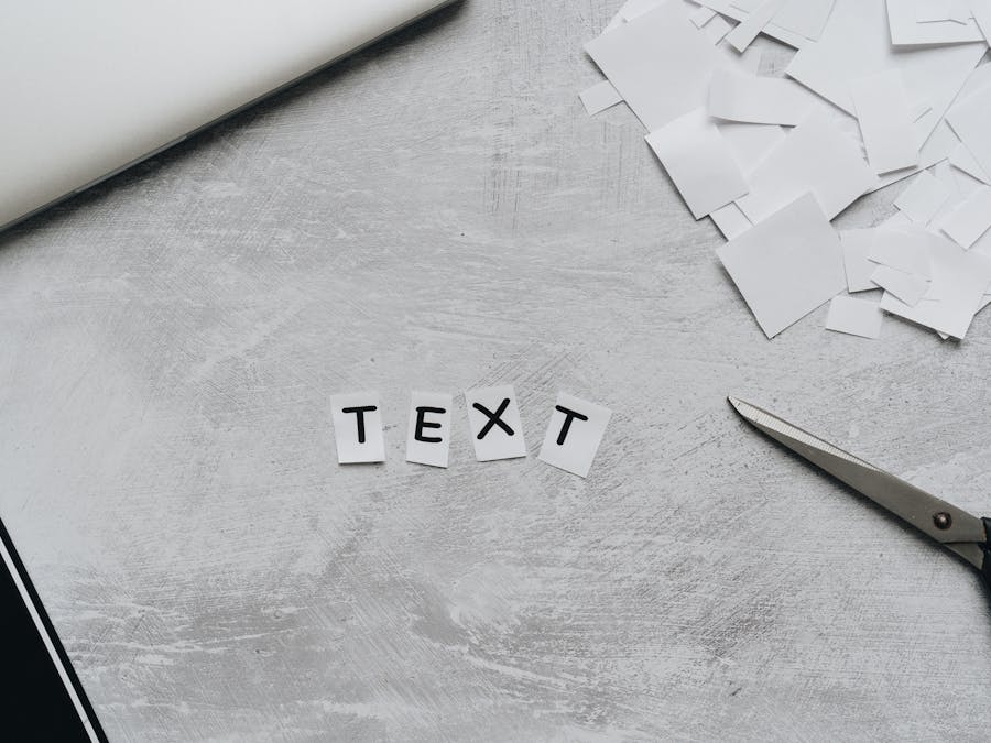 A flat lay of a creative workspace featuring cutout text, scissors, and paper pieces on a textured surface.