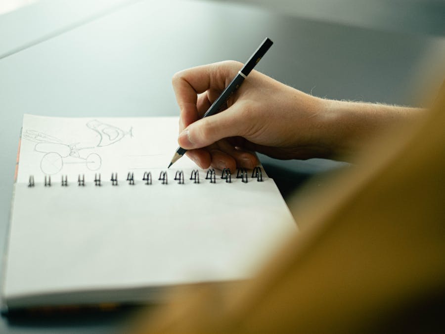 Hand sketching in a notebook with a pencil, focusing on creativity and planning.