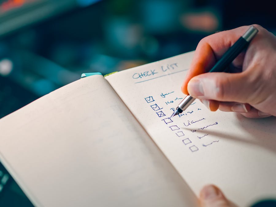 Close-up of a hand writing in a notebook with a checklist for effective task management.