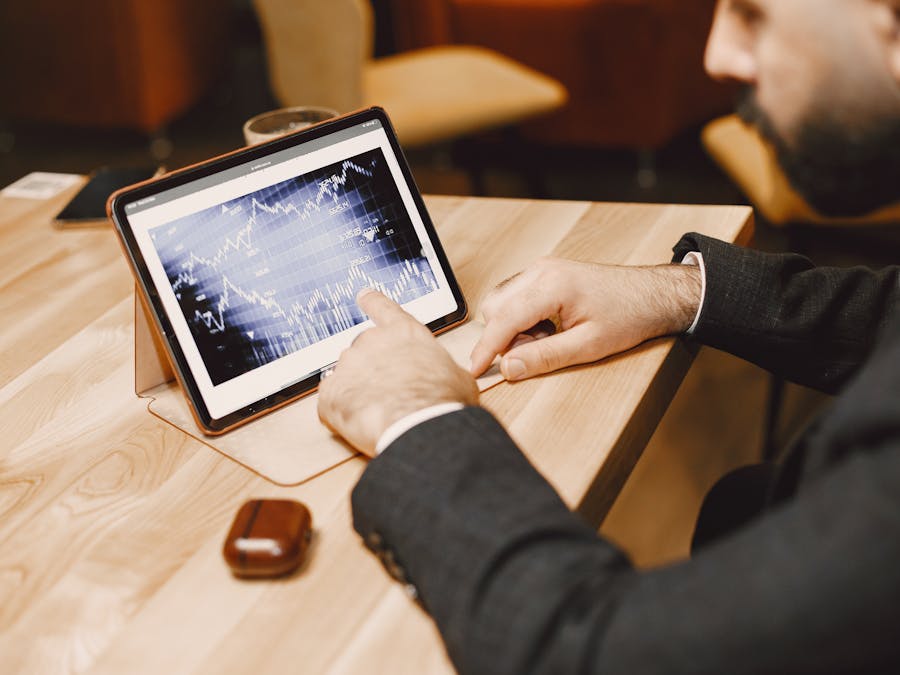 Business professional reviewing stock market data on a tablet in a modern office setting.