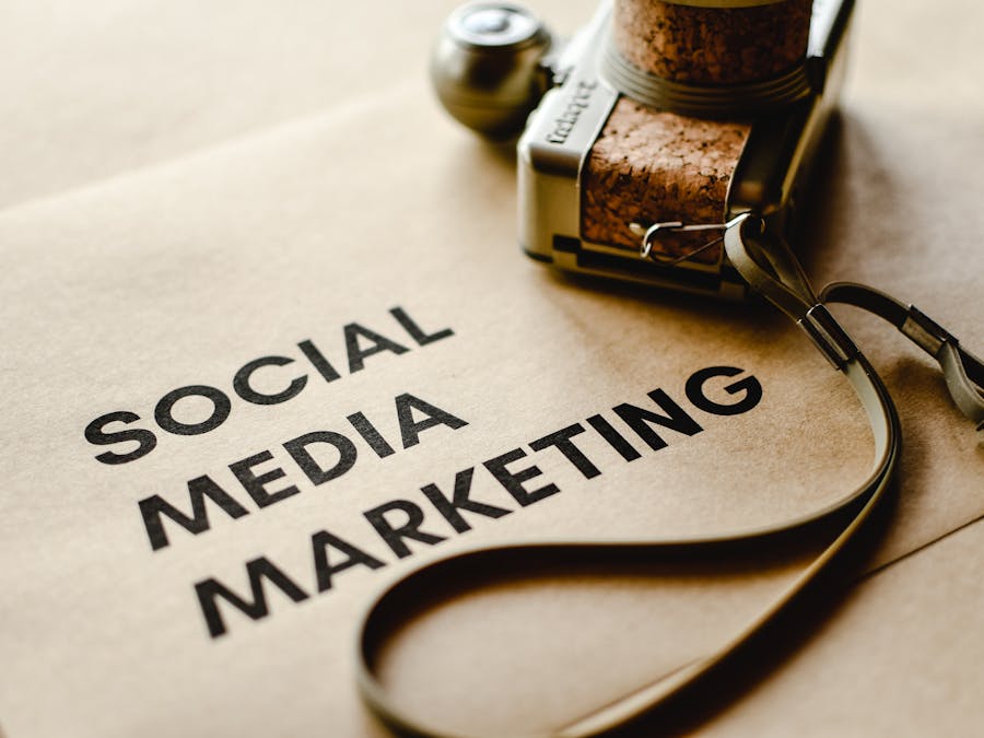 Close-up of a camera placed on brown paper with 'Social Media Marketing' text, emphasizing digital marketing themes.