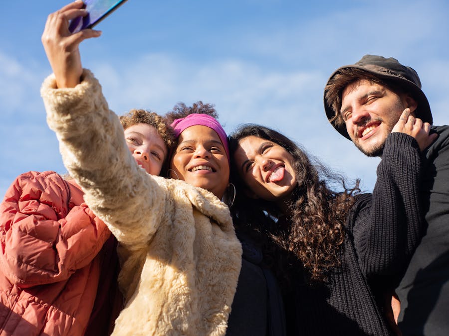 A joyful group of diverse friends taking a selfie outdoors on a sunny day.