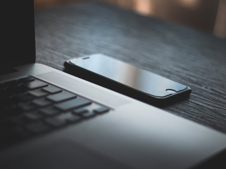 Modern laptop and smartphone on a textured wooden desk, capturing the essence of contemporary technology.