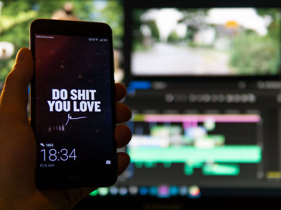 Close-up of a smartphone displaying an inspirational message against a video editing background.