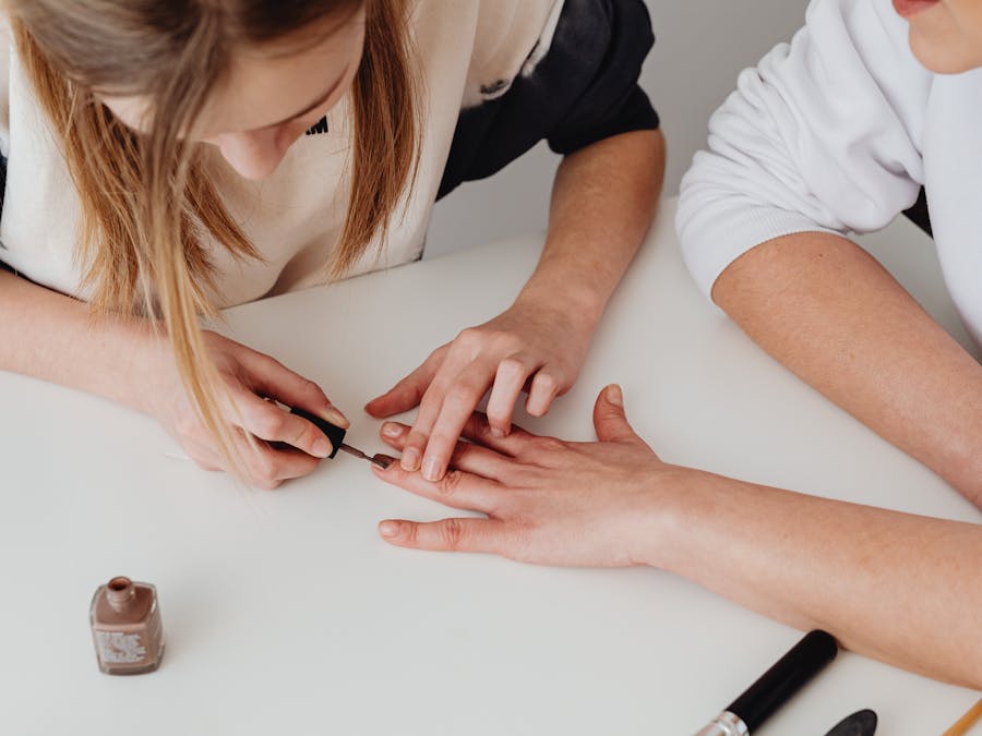 Close-up of a professional manicure being applied on a woman's hand at a salon.