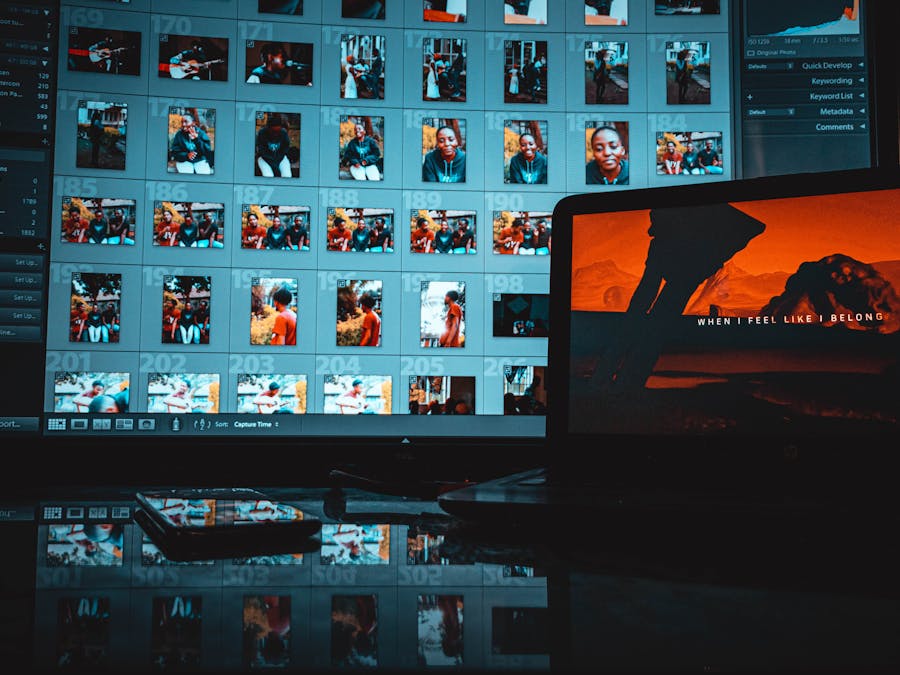 A modern creative workspace featuring a laptop and monitor displaying digital images and editing software.