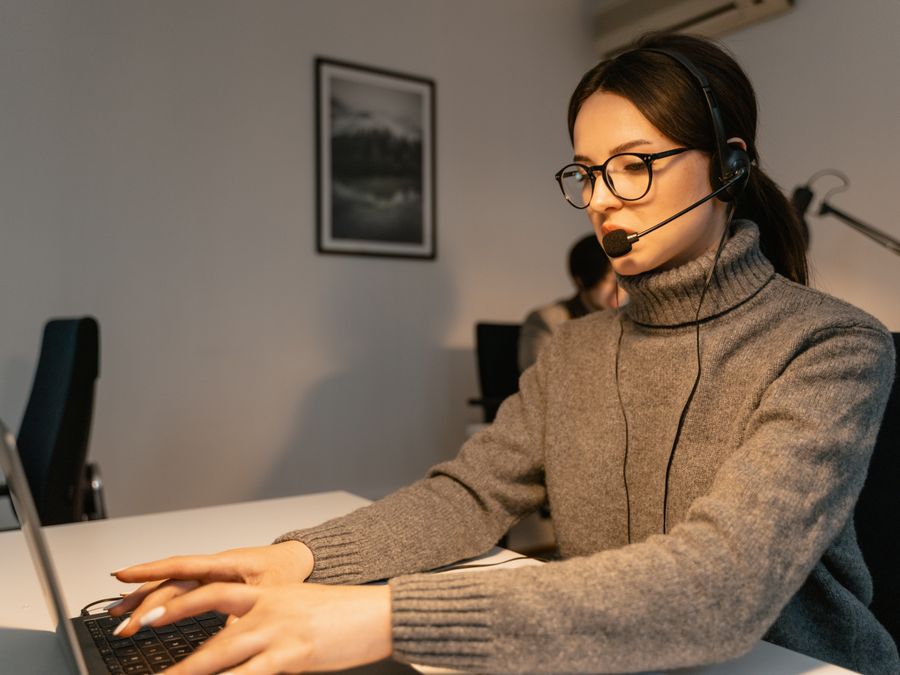 Woman in a call center providing customer support with a headset and laptop.