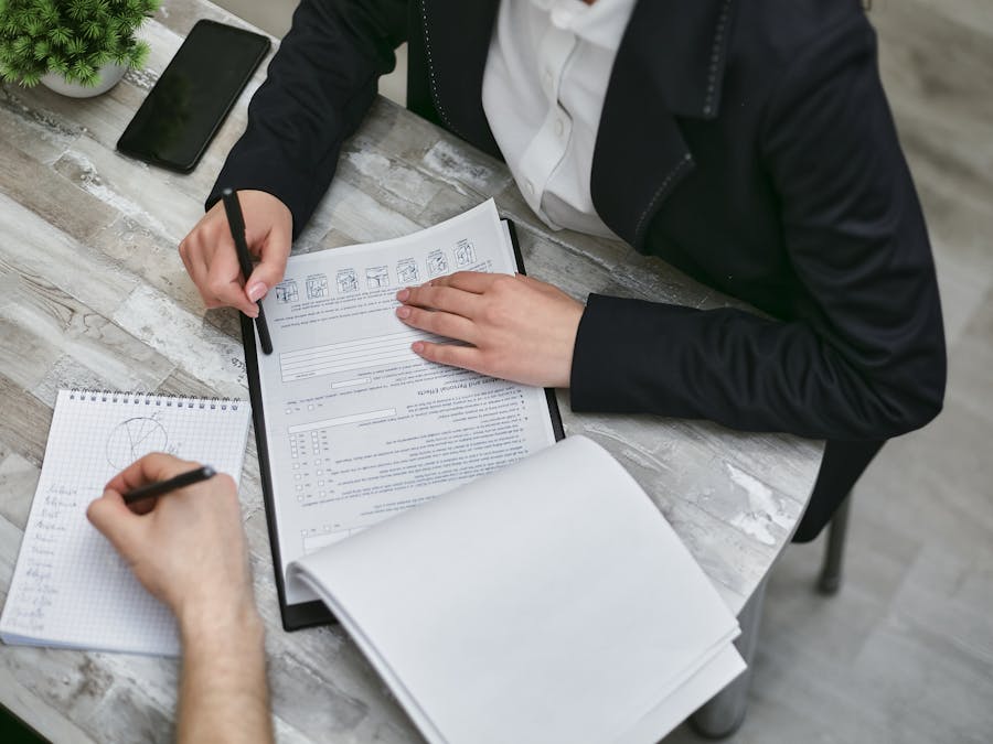 Two colleagues reviewing documents and taking notes during a business meeting.