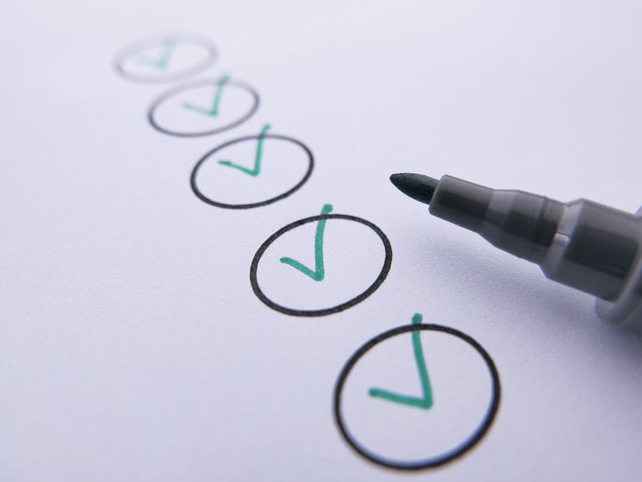 Close-up of a checklist with green checkmarks on white paper using a marker.