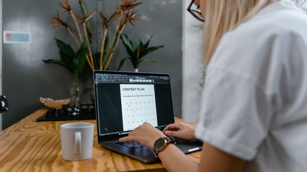 Focused woman typing on laptop while creating a content plan in a modern workspace.