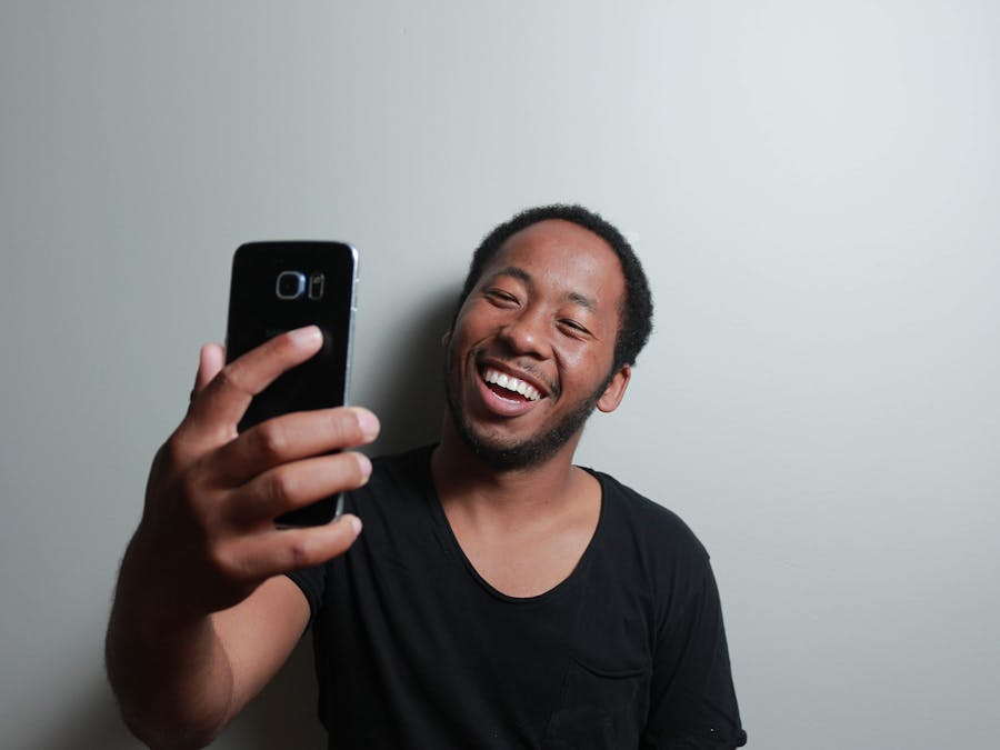 Happy man capturing a cheerful selfie with smartphone indoors.