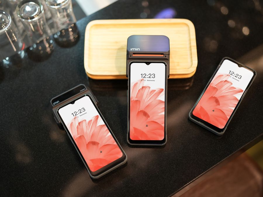 Close-up of three modern smartphones displaying a floral wallpaper, placed on a black surface.