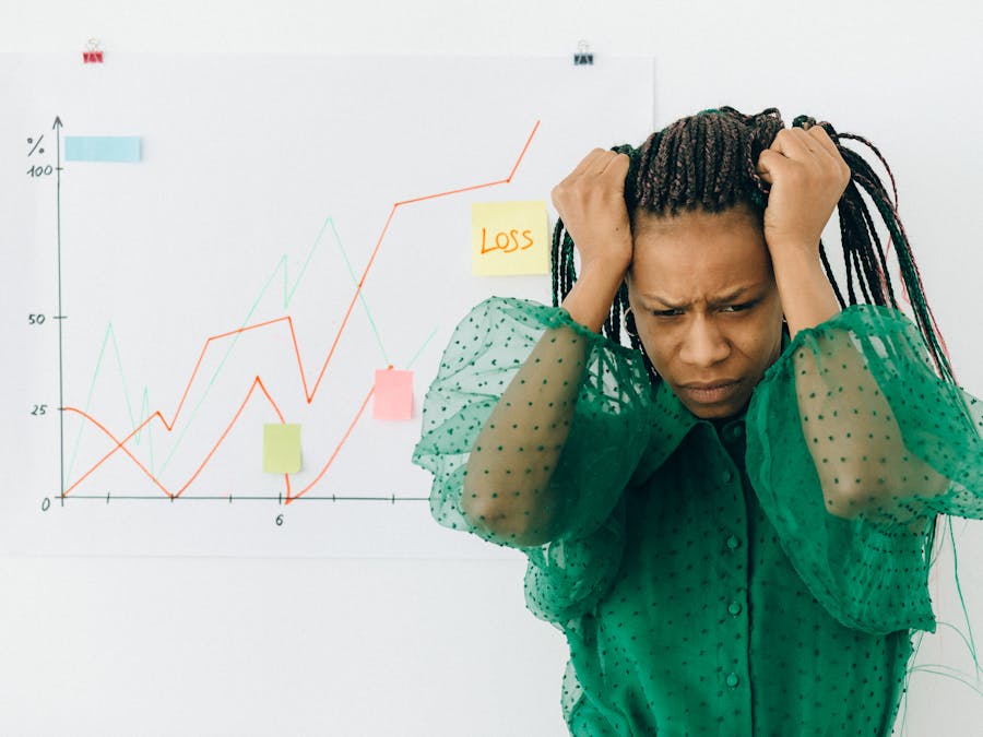 Frustrated businesswoman in green blouse analyzing a graph showing financial loss.