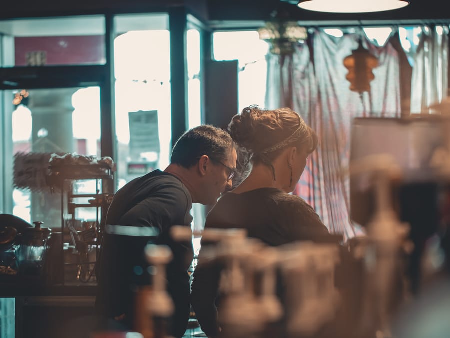 Two small business owners engaged in conversation within a warm, inviting cafe setting.