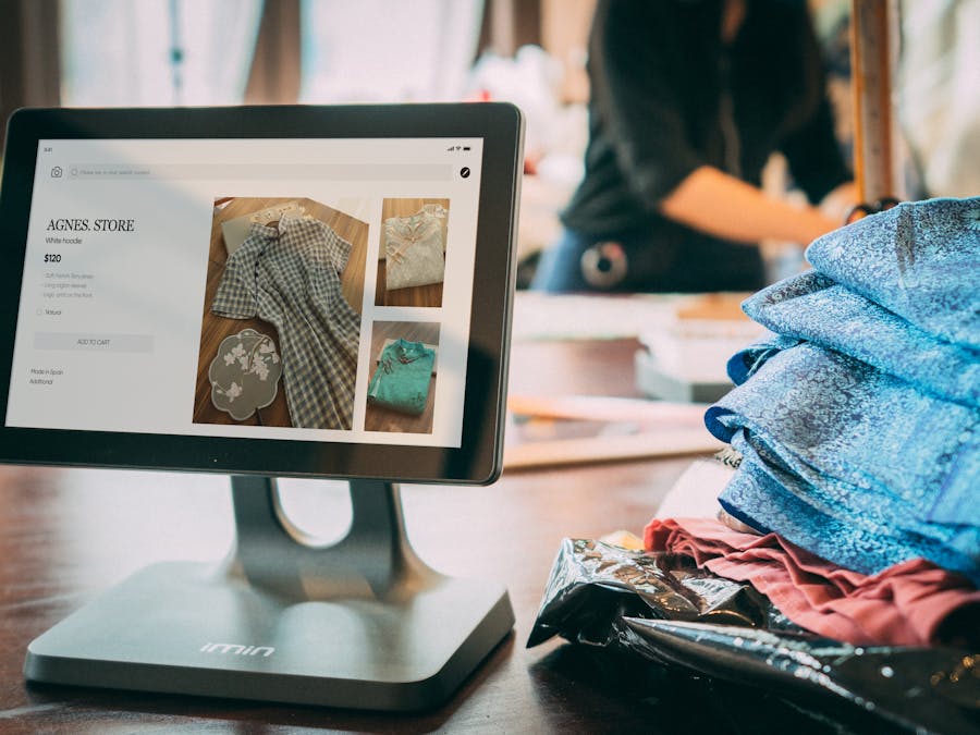 A digital point-of-sale system in a small fashion boutique with clothes displayed on a tablet.