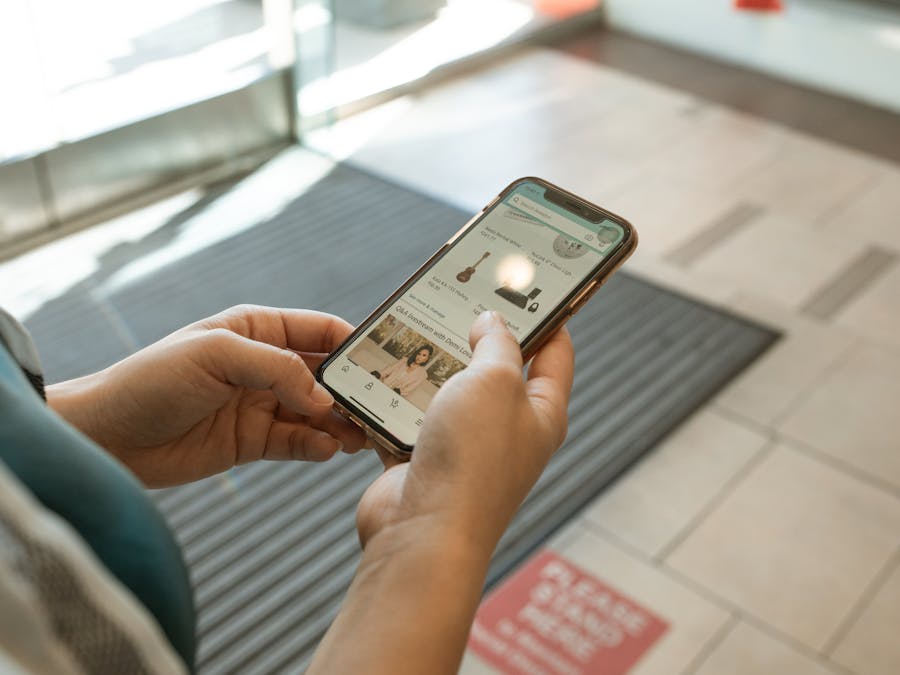 Close-up of hands holding a smartphone displaying an online shopping app in an indoor setting.