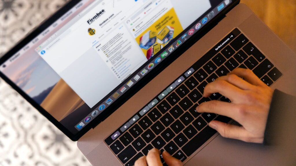 Hands typing on a laptop at a desk, engaging in online work, and navigating social media.