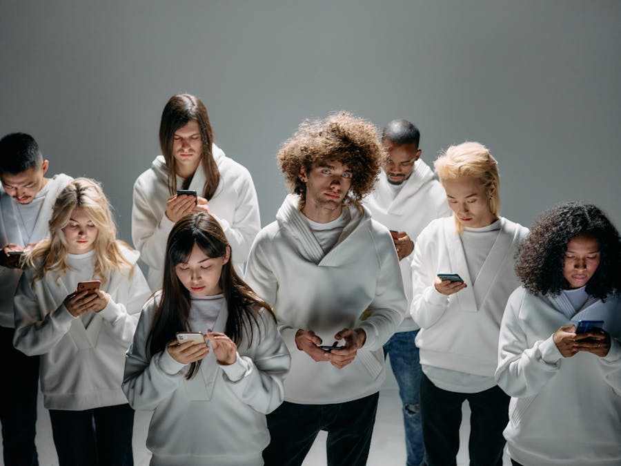 A group of diverse young adults focused on smartphones, symbolizing modern technology and digital connection.