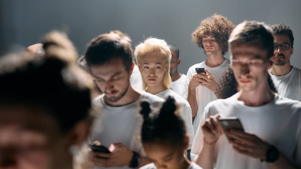 A diverse group of people looking at smartphones, illustrating social isolation in modern technology.