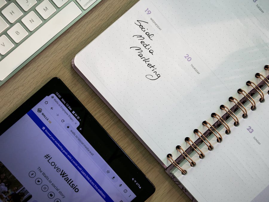 Top view of a notebook, tablet, and keyboard used for social media marketing planning.