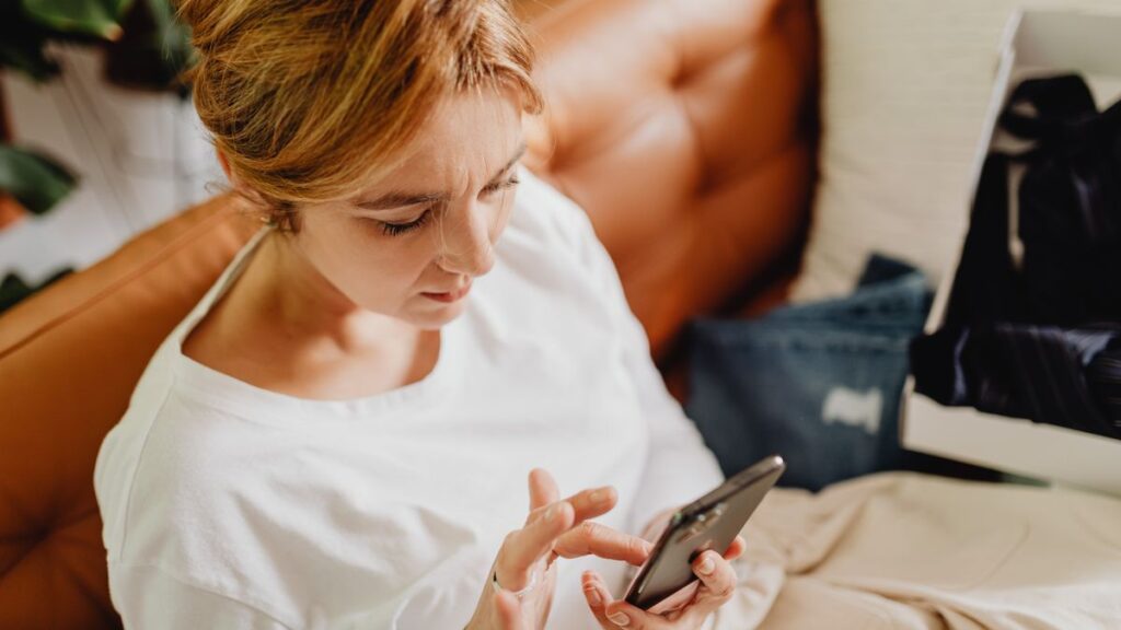 Woman sitting on a sofa using a smartphone at home.