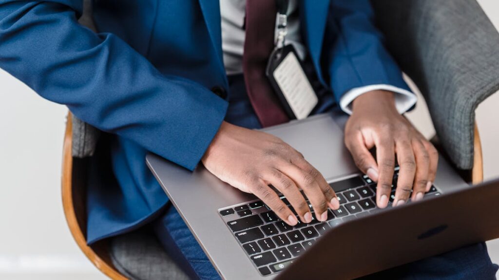 Close-up of a businessman in a blue suit working on a laptop indoors.