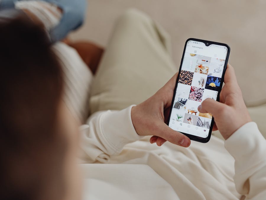 Person using smartphone to browse Instagram indoors, showing social media engagement.