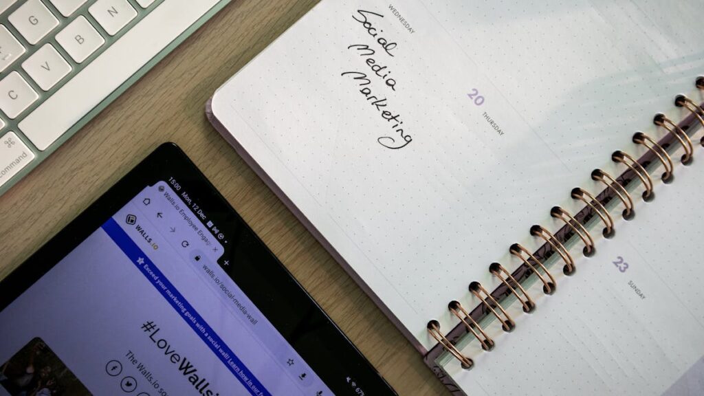 Top view of a notebook, tablet, and keyboard used for social media marketing planning.