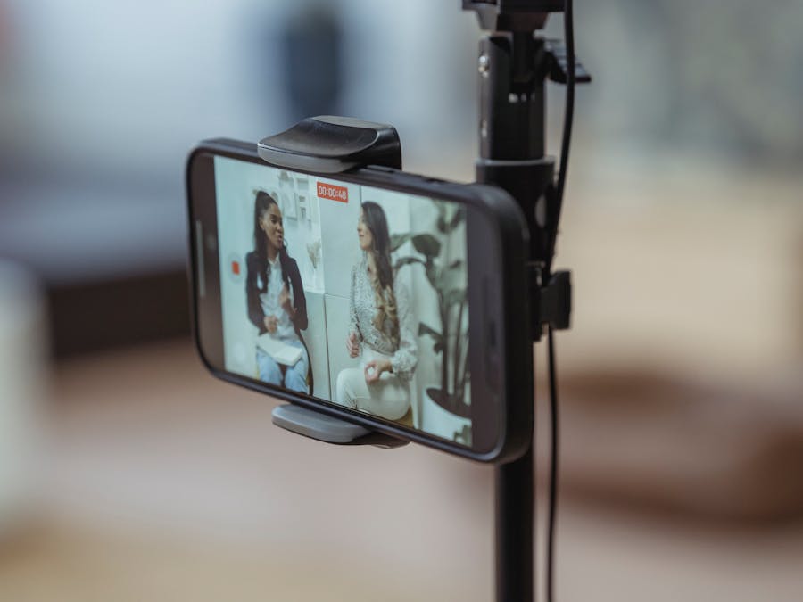 Modern smartphone on tripod recording video of content stylish women having friendly conversation