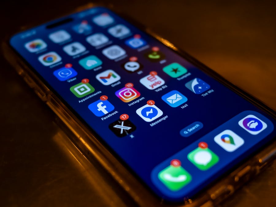 Smartphone screen displaying social media app notifications in a dimly lit setting.