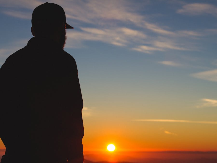 A silhouette of a man against a vibrant sunrise sky, symbolizing solitude and introspection.