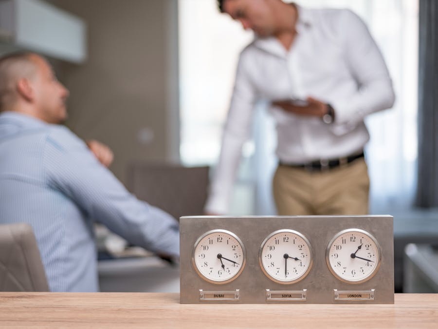 Two businessmen in an office with clocks displaying Dubai, Sofia, London time.