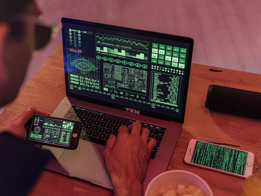 Man working with cybersecurity software on laptop and smartphone.