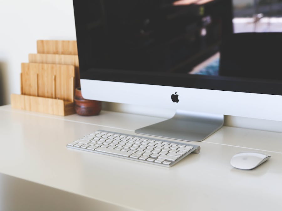 A clean and modern home office workspace featuring an iMac, keyboard, and magic mouse on a minimalist desk.