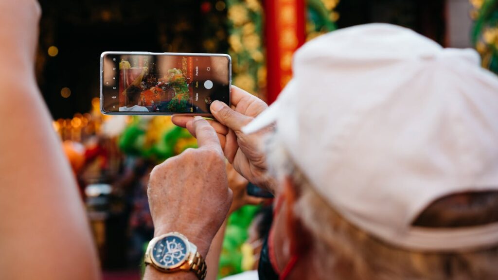 A person captures a vibrant street event with a smartphone, focusing on details and colors.