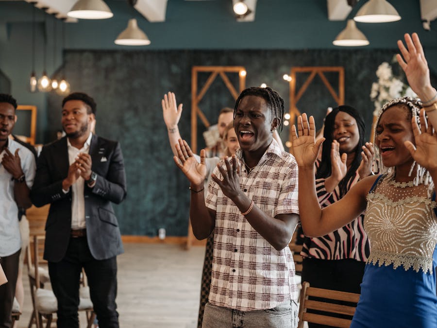 A joyful and diverse group of adults clapping and singing in a lively indoor setting.