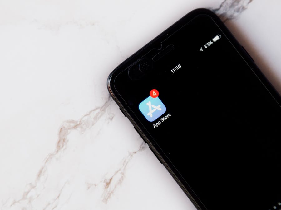 Close-up of an iPhone showing a notification on the App Store icon against a marble background.