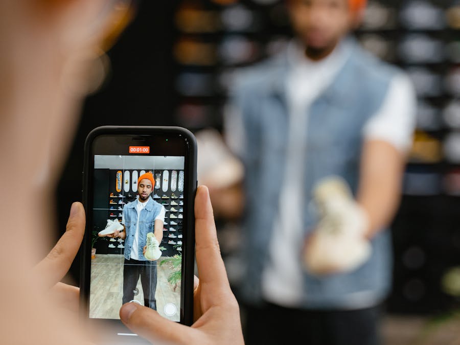 Man reviewing sneakers in-store captured on smartphone, showcasing footwear.