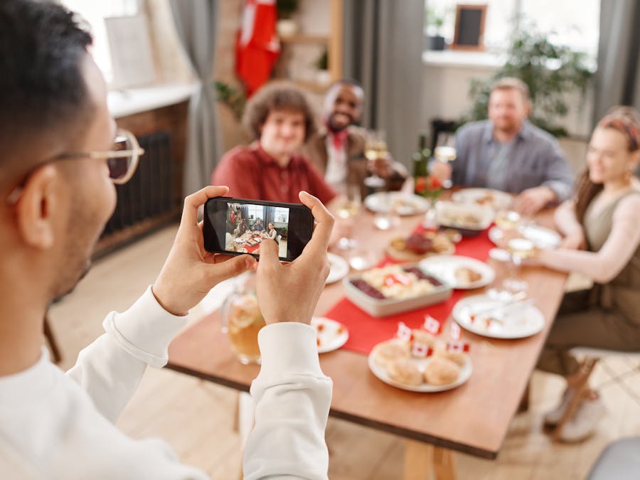 A person photographing a cheerful family gathering with a smartphone indoors.