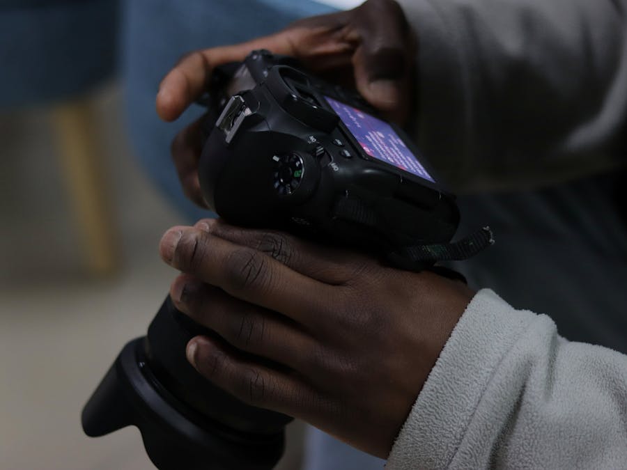 Close-up of an adult handling a DSLR camera indoors, focusing on photography details.