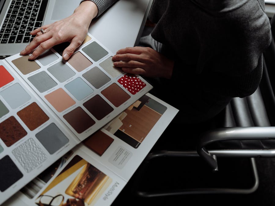 Interior designer on laptop reviewing color swatches for design project. Overhead view, modern workspace.