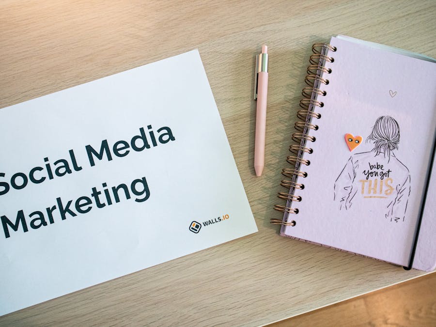 Flat lay of social media marketing paper and motivational notebook on wooden desk.