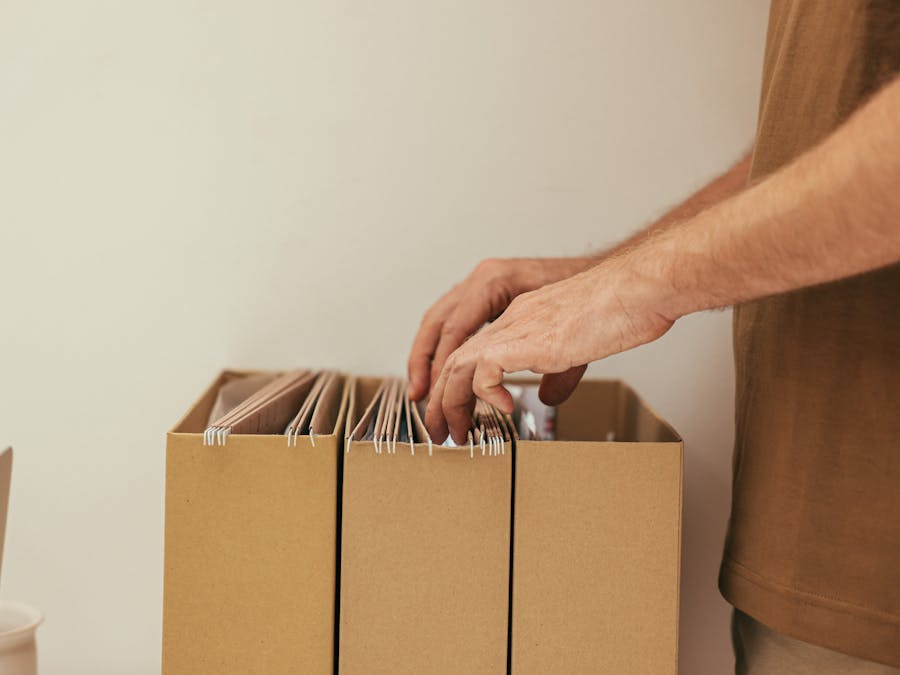Close-up of a person organizing files in cardboard boxes, ideal for business and office themes.