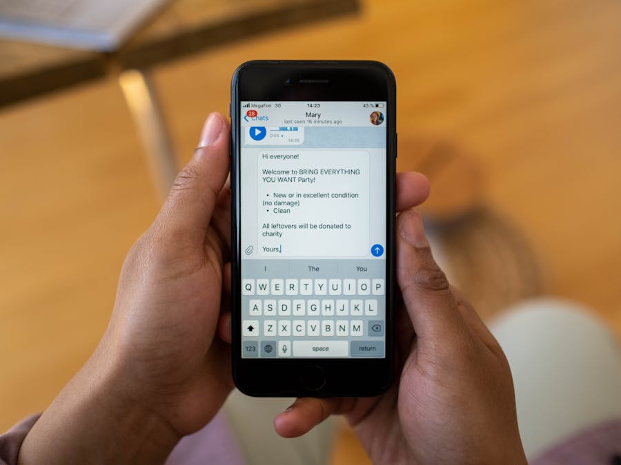 Person holding a smartphone displaying a text message about a party event indoors.