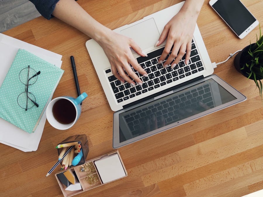 Aerial view of a contemporary desk setup with a laptop, coffee, and accessories, emphasizing productivity.