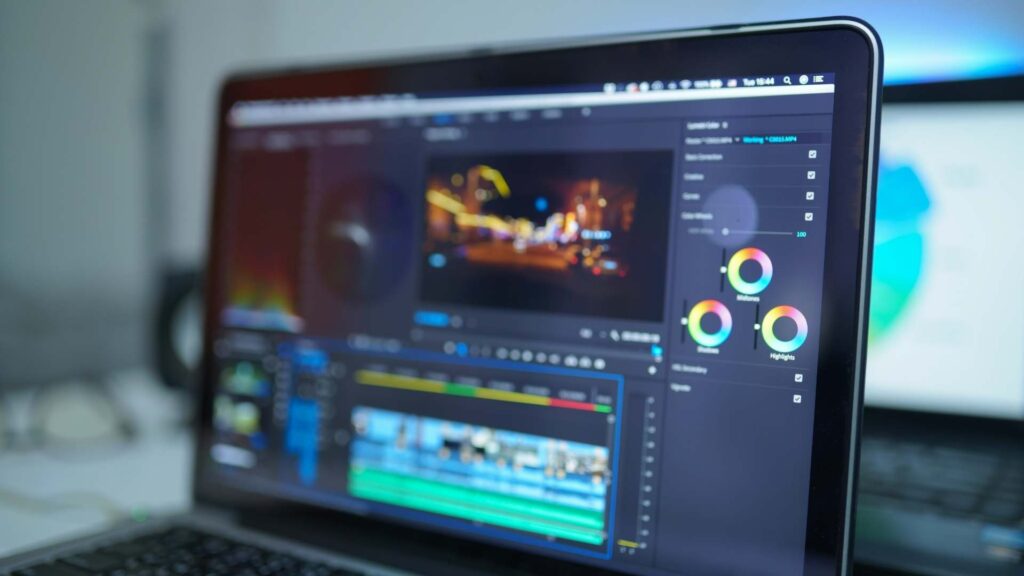 Video editing software open on a laptop with timeline and color correction controls